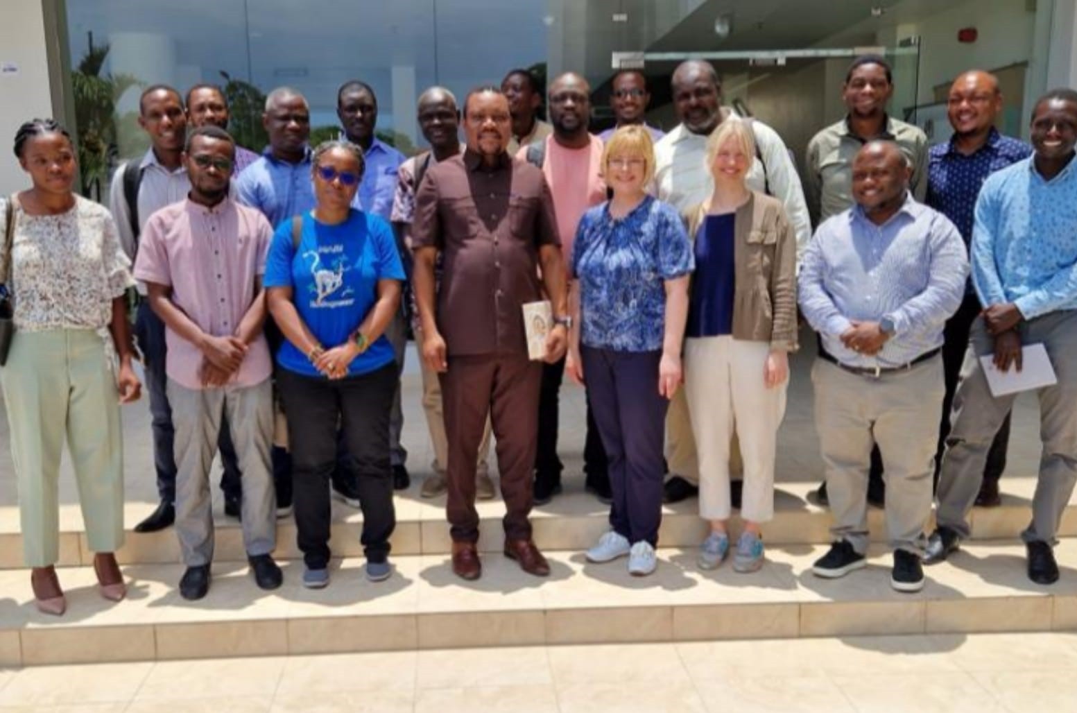 A diverse group poses for a photo on the steps outside a modern building. A diverse group poses for a photo on the steps outside a modern building.