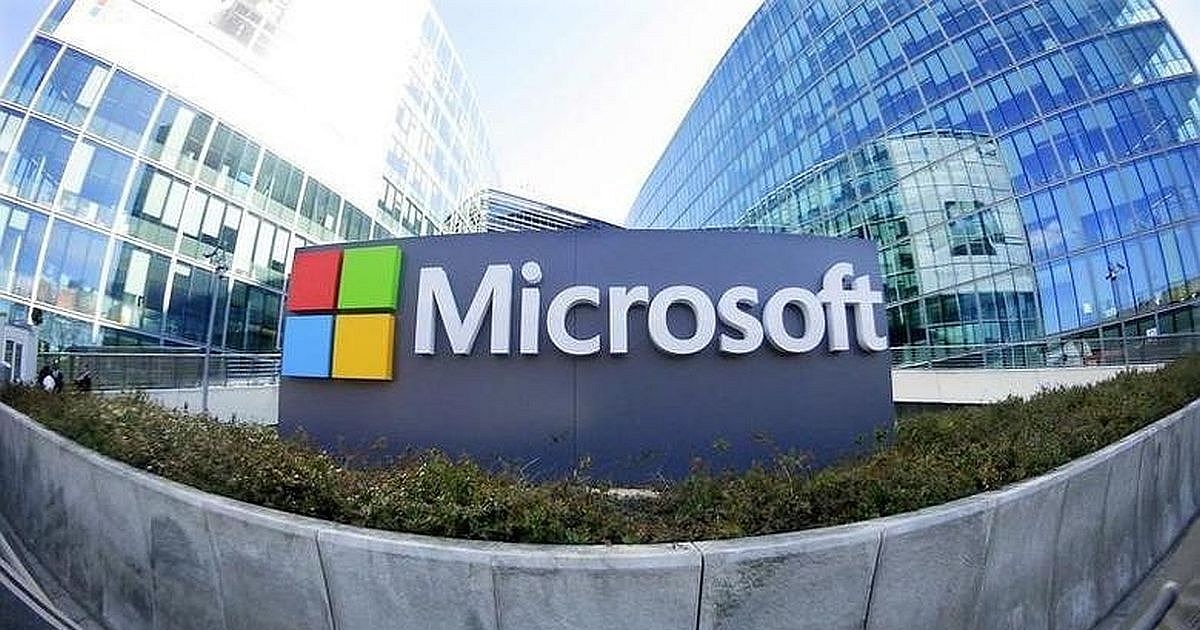 Microsoft logo sign displayed outdoors before modern glass office buildings. Microsoft logo sign displayed outdoors before modern glass office buildings.