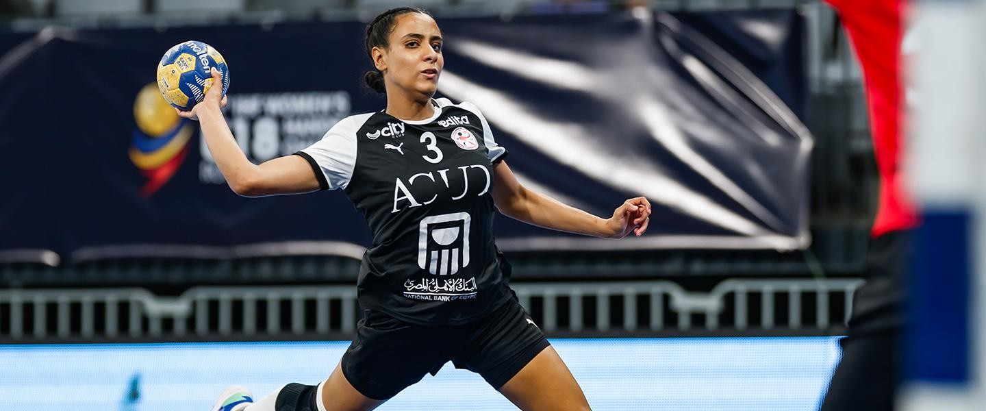 Female handball player in black jersey #3 holds ball on indoor court. Female handball player in black jersey #3 holds ball on indoor court.