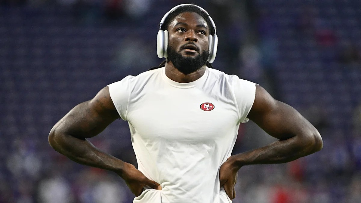 A man in a white SF-branded shirt and headphones stands with hands on hips in a stadium. A man in a white SF-branded shirt and headphones stands with hands on hips in a stadium.
