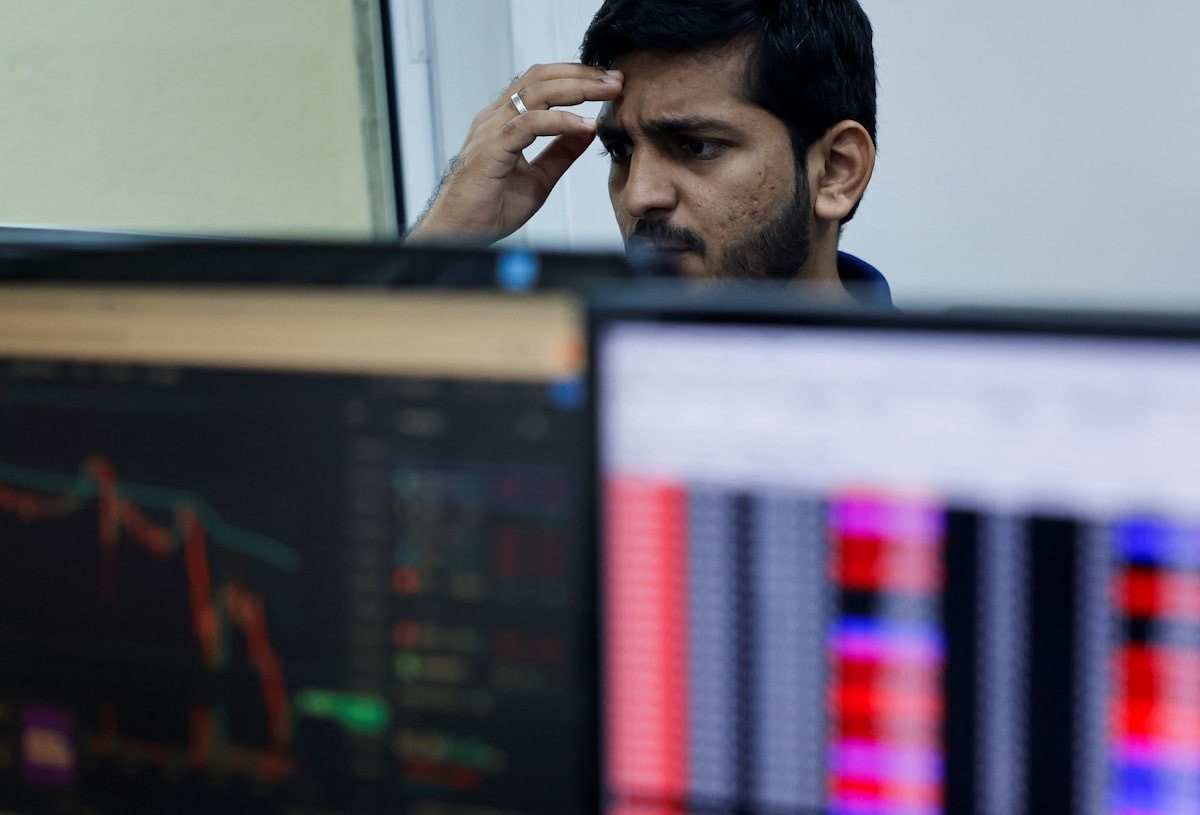 A man stares at financial data on computer monitors in an office. A man stares at financial data on computer monitors in an office.