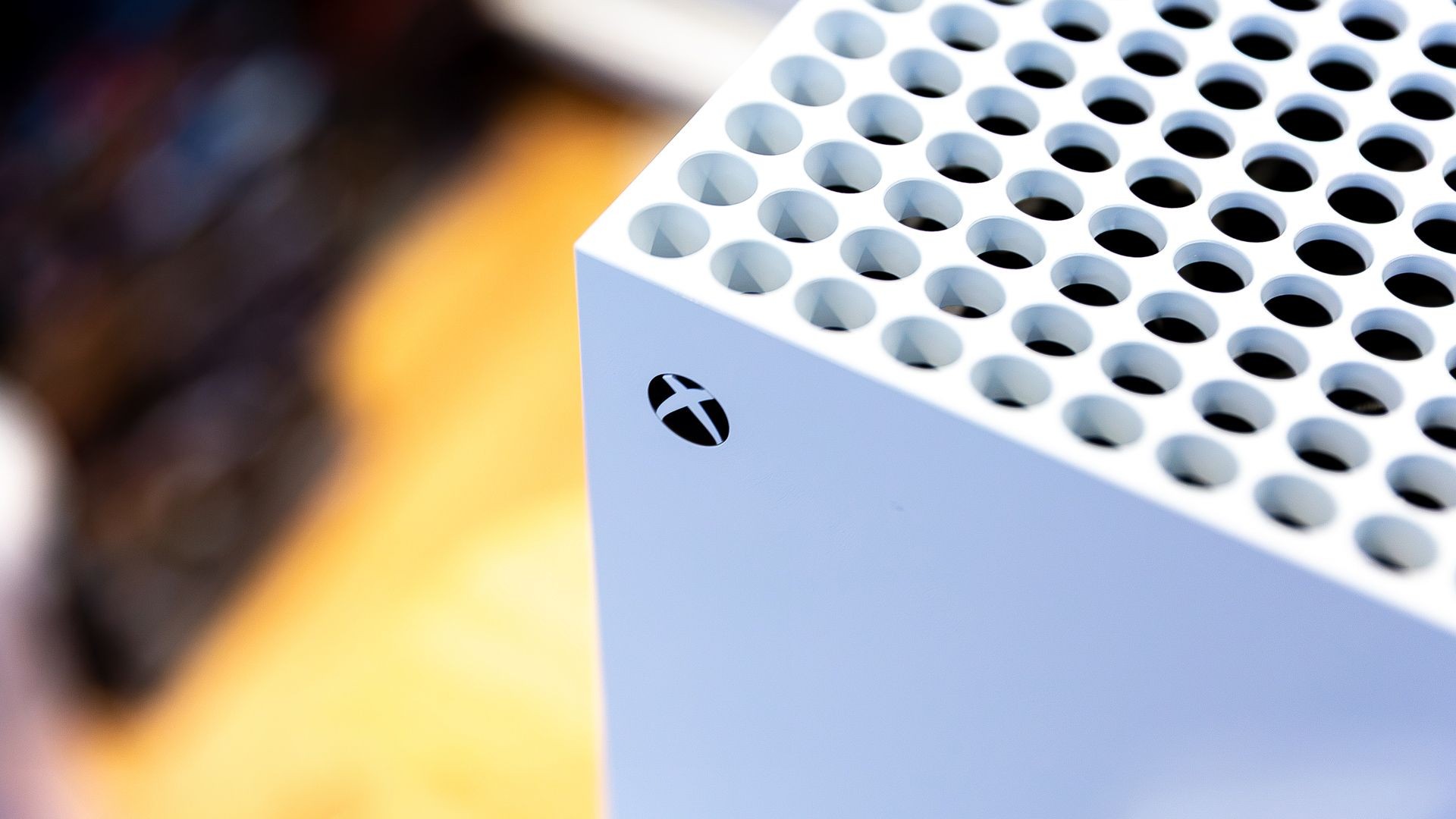 A white rectangular device with circular perforations and a logo on its side against a blurred background. A white rectangular device with circular perforations and a logo on its side against a blurred background.