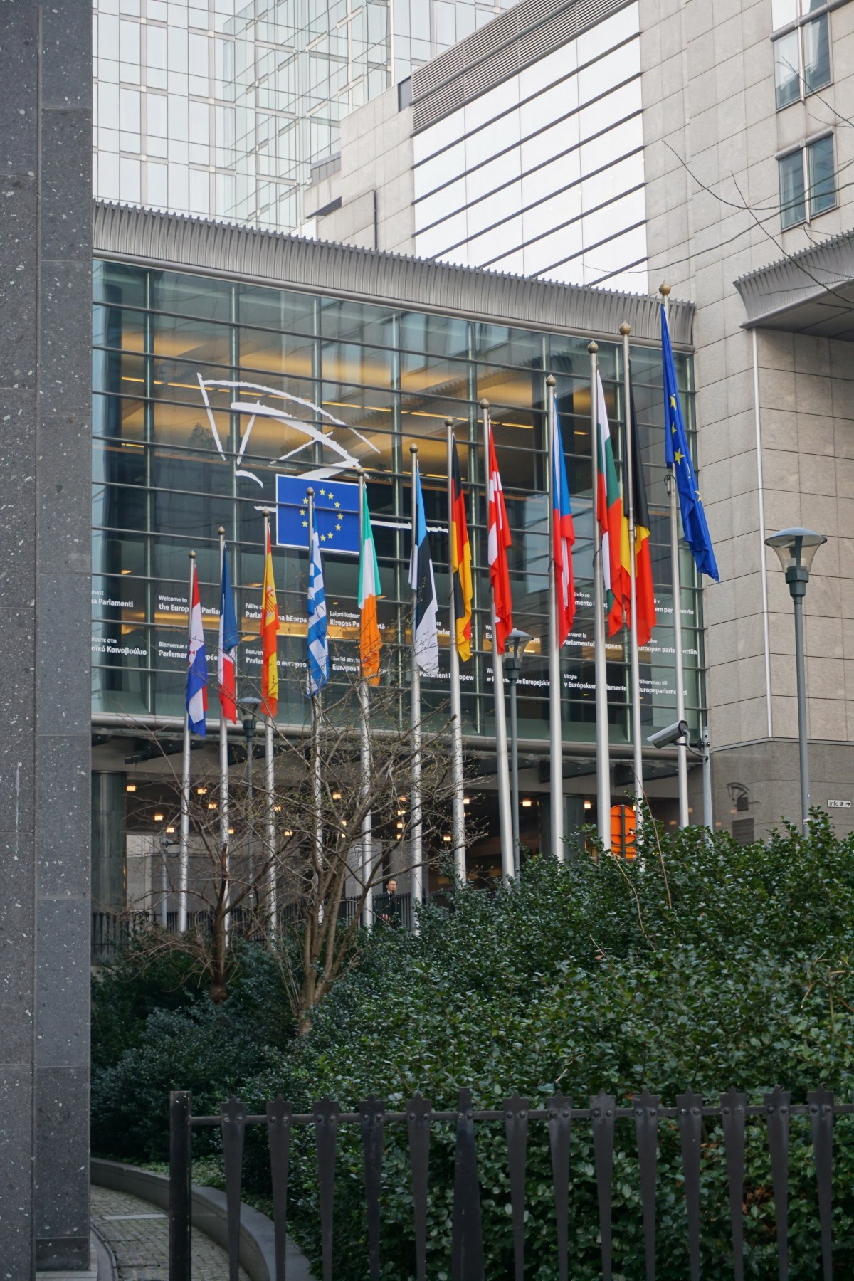 European Parliament building exterior features multiple national and EU flags on display. European Parliament building exterior features multiple national and EU flags on display.