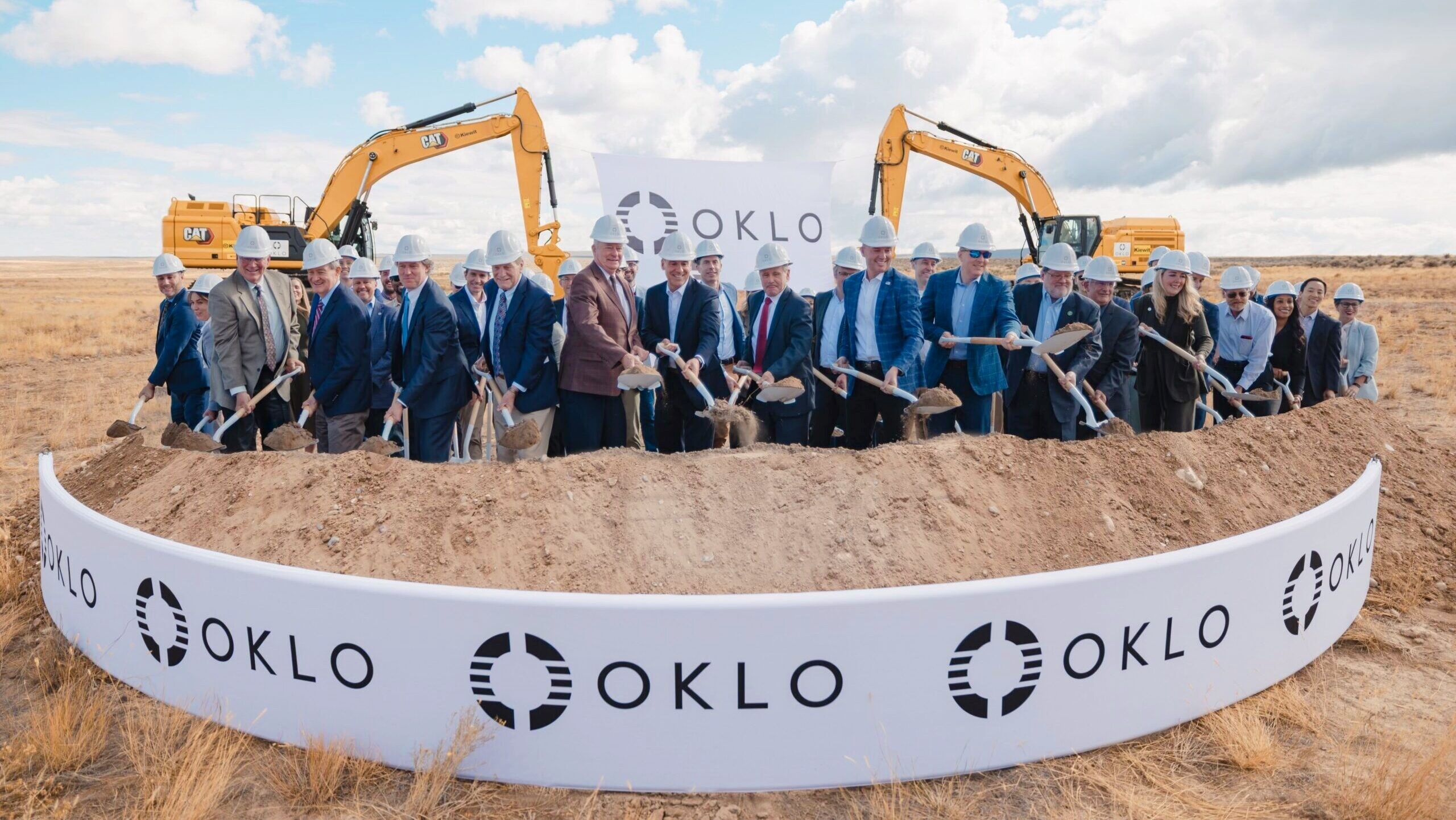 Group of people in hard hats hold shovels during OKLO's groundbreaking ceremony in an open field. Group of people in hard hats hold shovels during OKLO's groundbreaking ceremony in an open field.