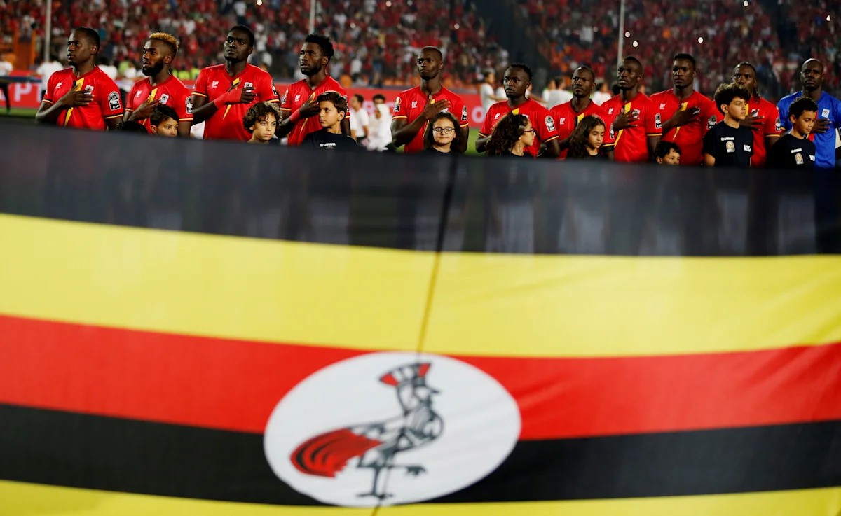Ghana national football team stands in stadium behind flag with yellow, red, black stripes and rooster emblem, hands over hearts. Ghana national football team stands in stadium behind flag with yellow, red, black stripes and rooster emblem, hands over hearts.