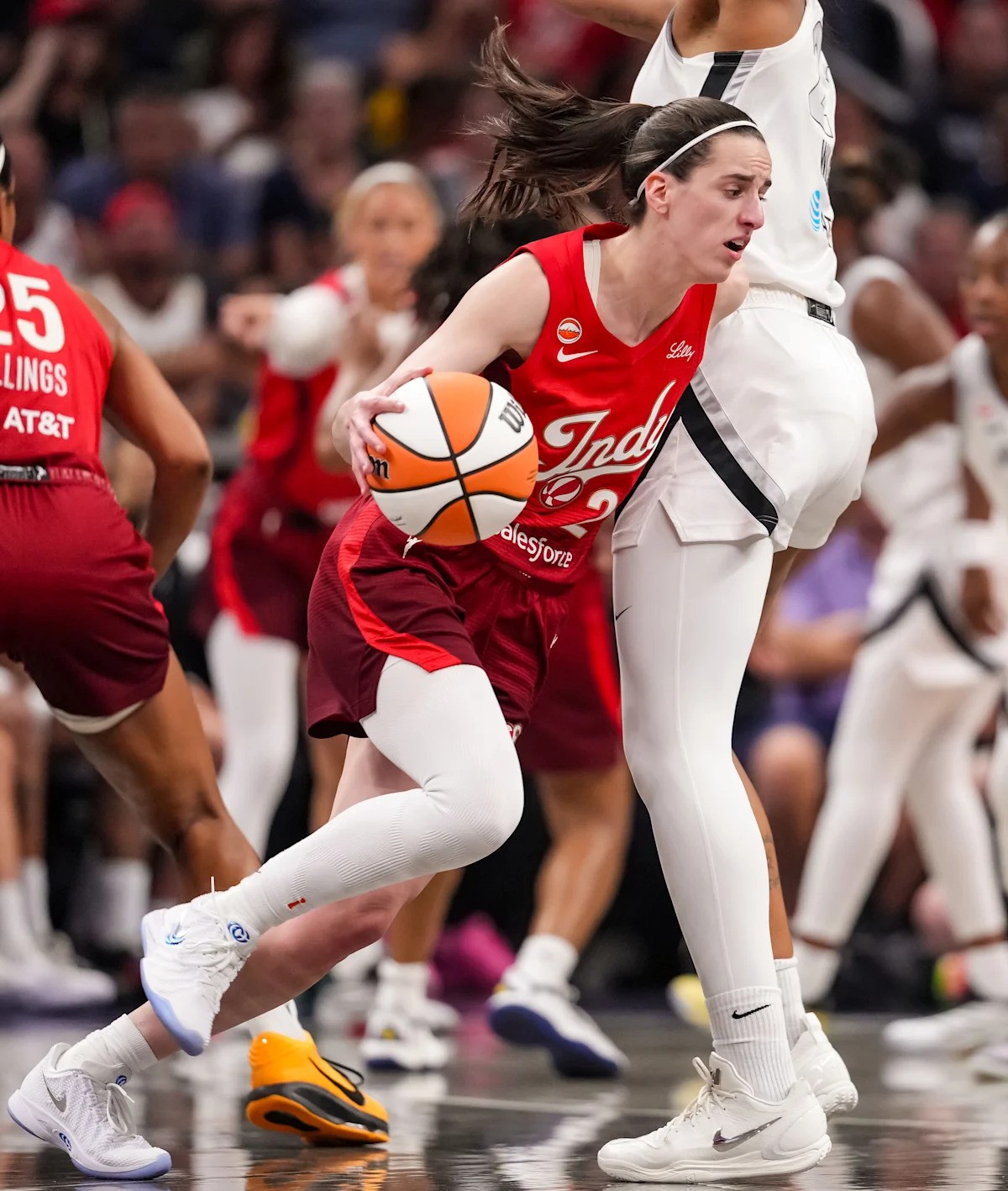 A female basketball player in a red Indiana jersey dribbles while being defended on an indoor court. A female basketball player in a red Indiana jersey dribbles while being defended on an indoor court.