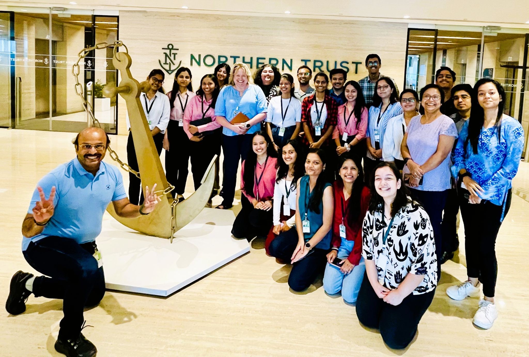 Group poses for photo at Northern Trust office with anchor sculpture visible.
