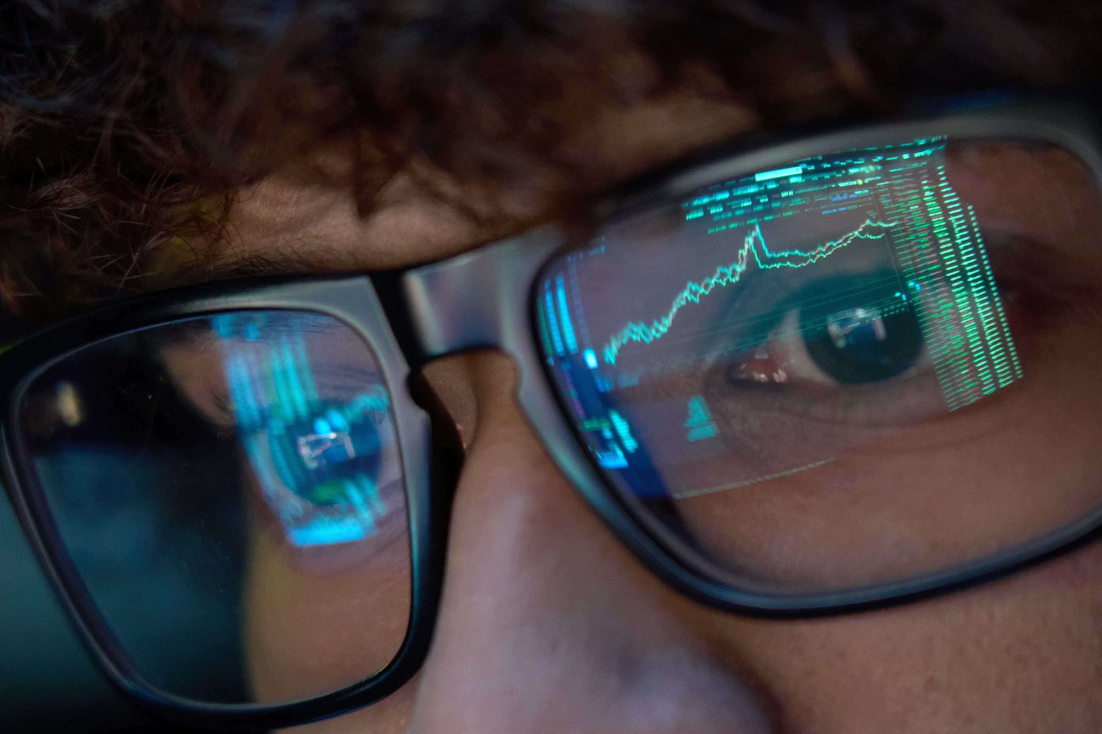 Person wears AR glasses showing financial chart and code in a close-up. Person wears AR glasses showing financial chart and code in a close-up.