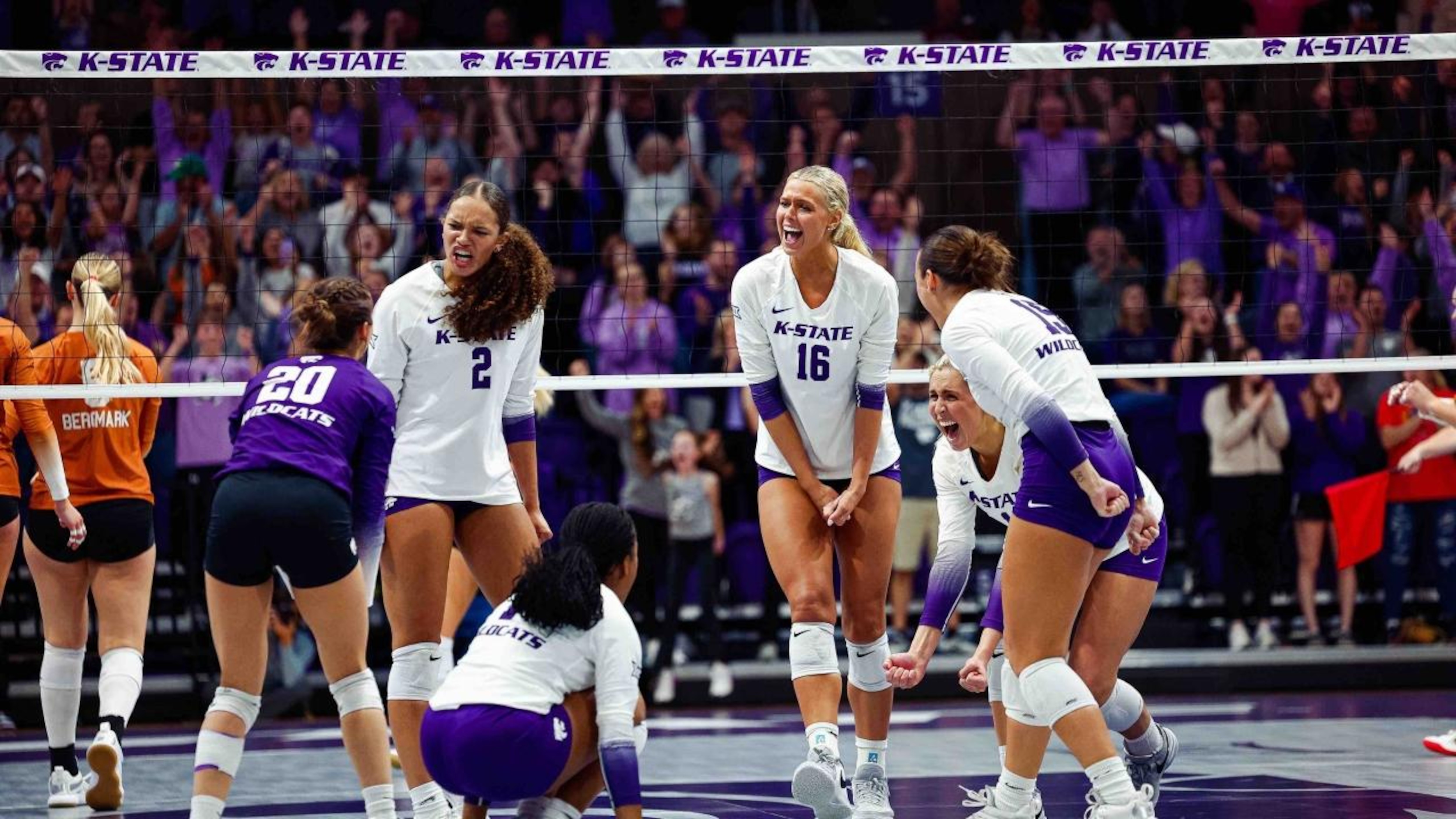 K-State volleyball team celebrates on an indoor court during a match with spectators. K-State volleyball team celebrates on an indoor court during a match with spectators.