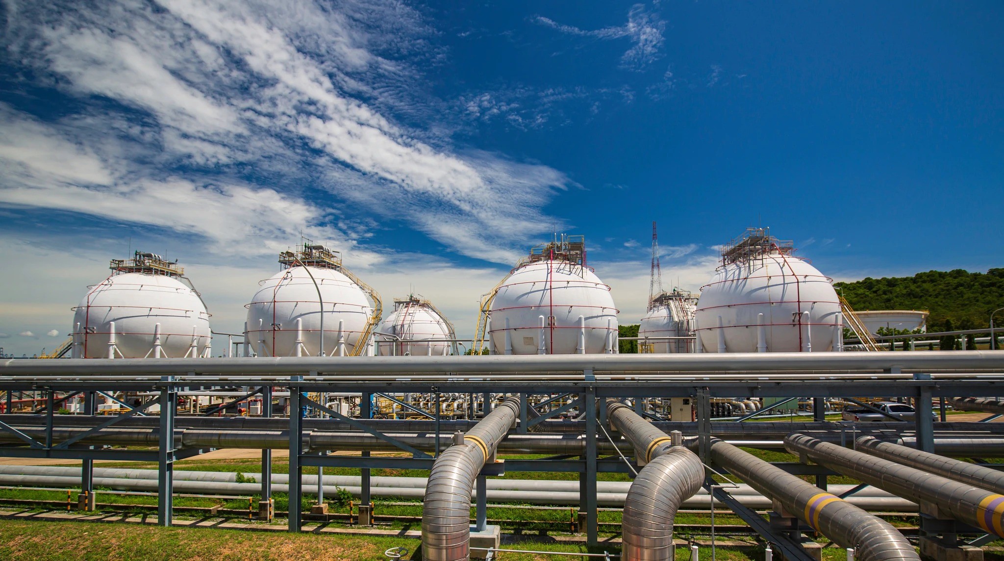White oil storage tanks and pipelines at an outdoor industrial facility under a clear blue sky. White oil storage tanks and pipelines at an outdoor industrial facility under a clear blue sky.