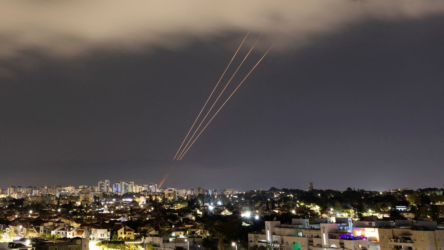 Nighttime urban skyline with three illuminated trajectories visible against dark clouds. Nighttime urban skyline with three illuminated trajectories visible against dark clouds.