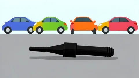 A fuel pump nozzle resting on a concrete surface next to a row of parked cars