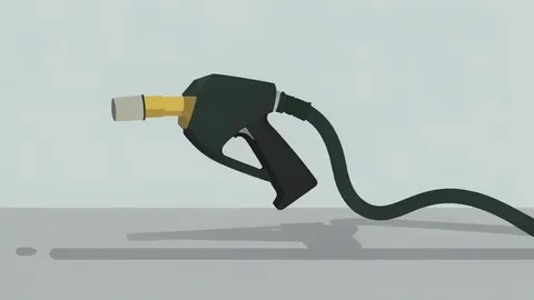 A grey gas pump nozzle resting on a textured concrete surface with a coiled hose.