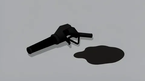 A fuel pump nozzle resting on a concrete surface next to a puddle of spilled liquid
