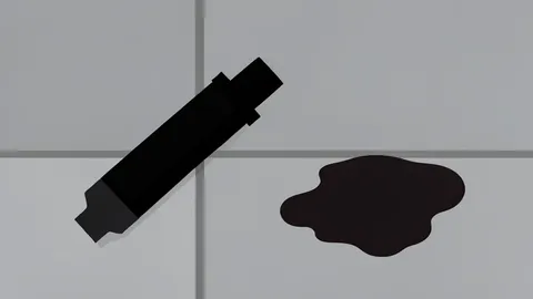 A fuel pump nozzle resting on a concrete surface next to a puddle of spilled liquid