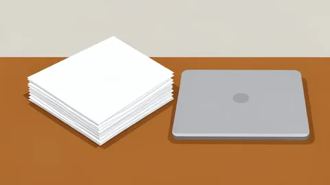 A stack of paper documents resting on a wooden desk next to a closed laptop