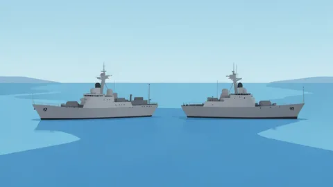 Two grey naval warships anchored in a calm blue harbor bay