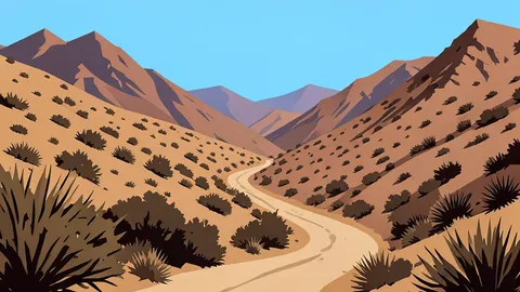 A winding dirt road cuts through an arid mountain valley with dry scrub vegetation.