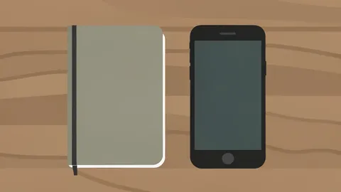 A closed hardcover notebook lying on a wooden desk next to a sleek, rectangular smartphone