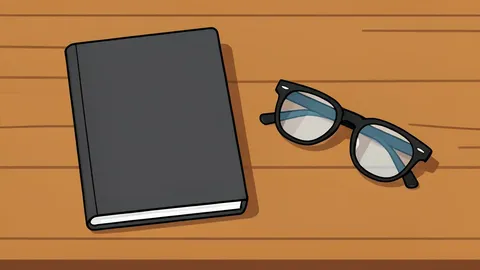 A closed notebook resting on a wooden desk next to a pair of reading glasses