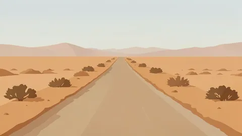A dusty, unpaved road stretching through a dry, arid landscape under a hazy sky.