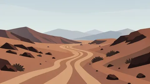 A rugged, arid landscape with winding dirt roads and distant mountain ranges under a hazy sky