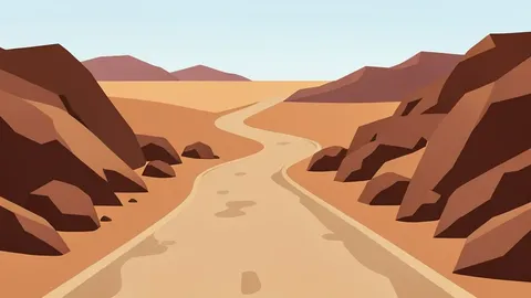 A dusty, unpaved road winding through arid, rocky terrain in a desert landscape