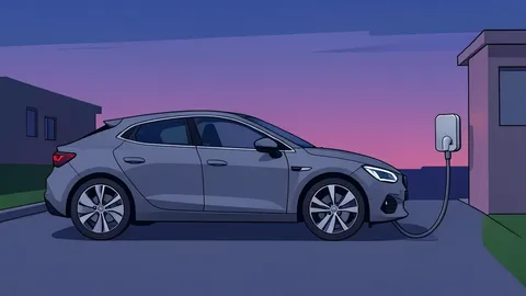 An electric vehicle connected to a wall-mounted charger in a driveway at dusk.