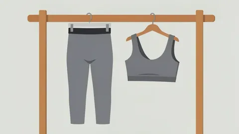 A pair of grey athletic leggings and a matching sports bra hanging on a wooden rack in a minimalist retail store