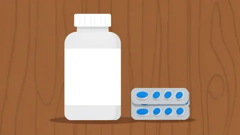 A white pill bottle with a plain label sitting on a wooden counter next to a small stack of blister packs