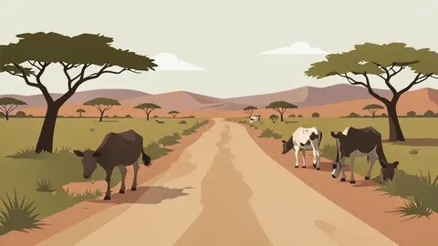 A dusty rural road in the Horn of Africa with livestock grazing nearby