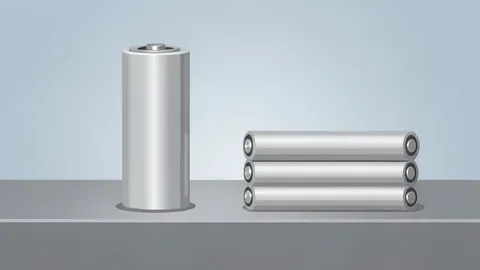 A cylindrical lithium-ion battery cell standing upright on a metal workbench next to a stack of similar cells