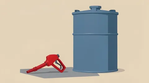 A fuel pump nozzle resting on a concrete surface next to a large industrial storage tank
