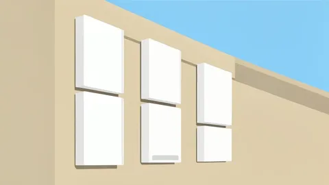 A row of white residential battery units mounted on the exterior wall of a house