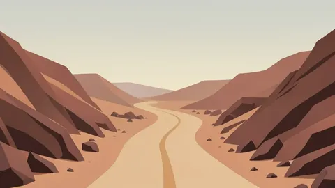 A dusty, unpaved road winding through arid, rocky terrain under a hazy sky
