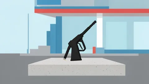 A fuel pump nozzle resting on a concrete island at a gas station
