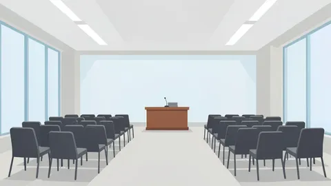 A wide-angle view of a modern conference hall with rows of empty chairs facing a central podium in a neutral, well-lit space.