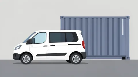 A white electric cargo van parked on an asphalt surface next to a large industrial shipping container
