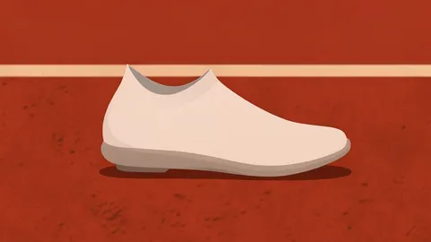 A pair of lightweight running shoes with a low-profile sole and seamless upper resting on a red clay track surface