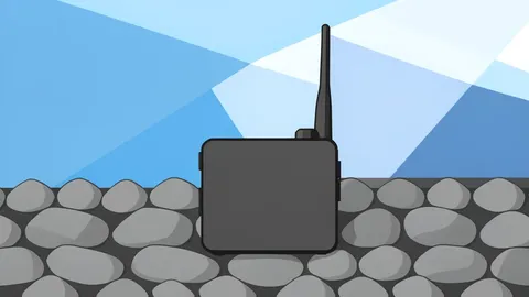 A rugged handheld communication device with an antenna resting on railway track ballast.