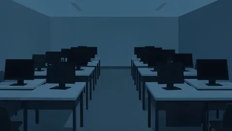 A dimly lit game development studio with rows of empty desks and computer monitors