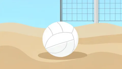 A white volleyball resting on a sandy beach court surface