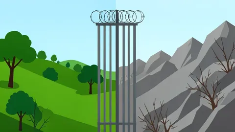 A border fence with barbed wire separating two distinct landscapes
