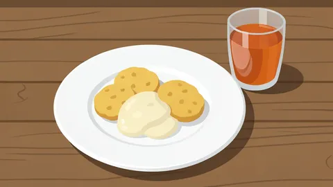 A rustic wooden table featuring a plate of biscuits with gravy and a glass of sweet tea.