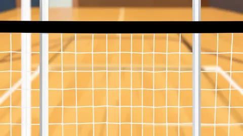 A high school gymnasium with a volleyball net stretched across the center of the court